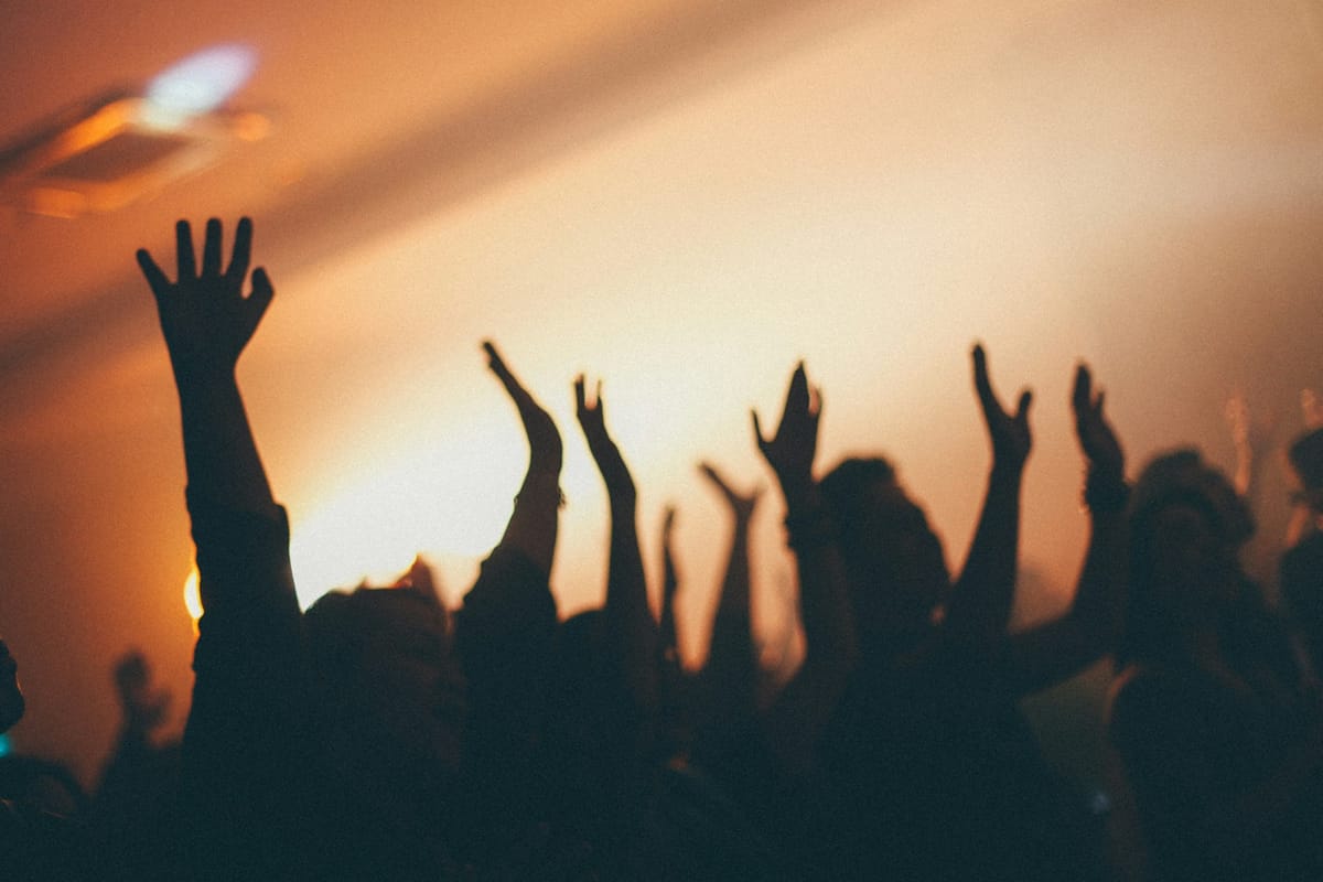 Silhouetted hands raised against a warm amber glow